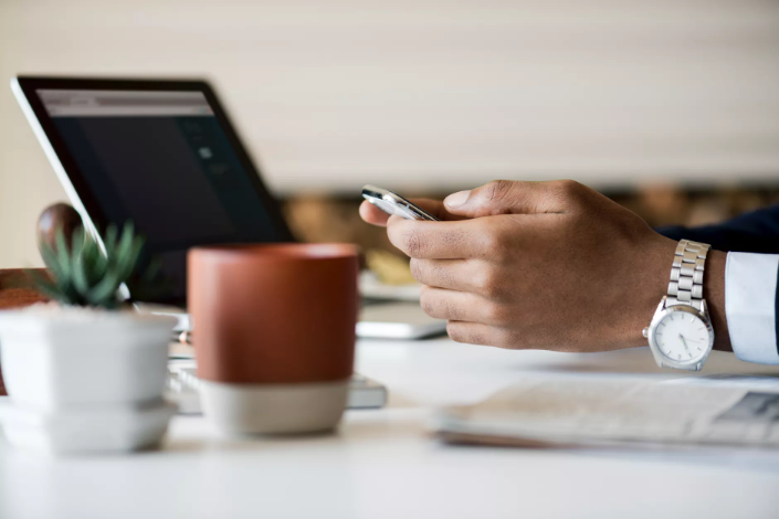 a person holding a phone in front of a laptop
